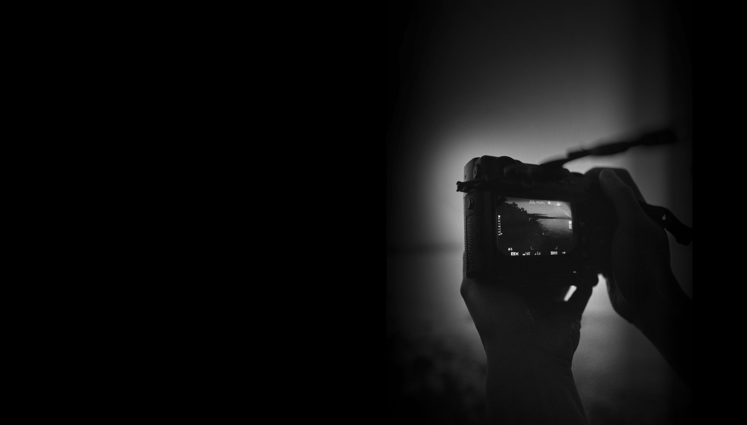 Schwarz Weiß Aufnahme von Händen, die eine Kamera halten. Man schaut von hinten auf die Kamera. Agentur für Kommunikationsdesign Ulrike Schwier.